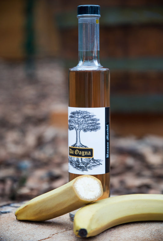Flasche Da Oagna Banane-Mandel-Likör mit Banane und Mandeln auf natürlichem Hintergrund