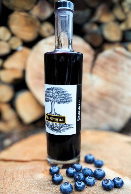 Heidelbeer-Likör von Da Oagna in stilvoller Flasche mit frischen Beeren und Vanilleschote im Hintergrund