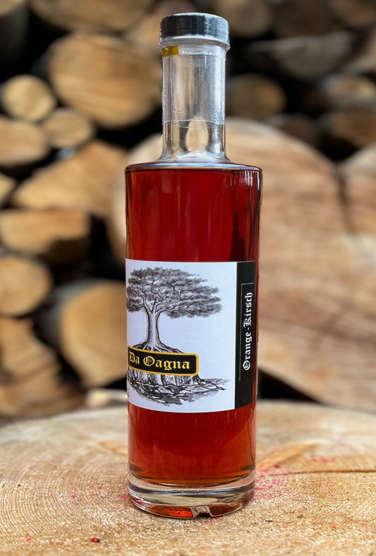 Flasche Orangen-Kirsch-Likör von Da Oagna mit Orangenstücken, Kirschen und Zimtstange auf Holzuntergrund