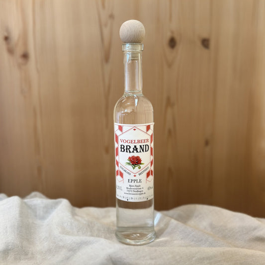 Vogelbeerbrand in einer Glasflasche von Schnapsvielfalt. Hochwertiger Brand aus reifen Vogelbeeren mit intensivem Fruchtaroma und herbem Geschmack, ideal für Liebhaber besonderer Obstbrände.